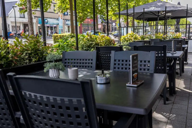 Het terras met zwarte tafels en groen